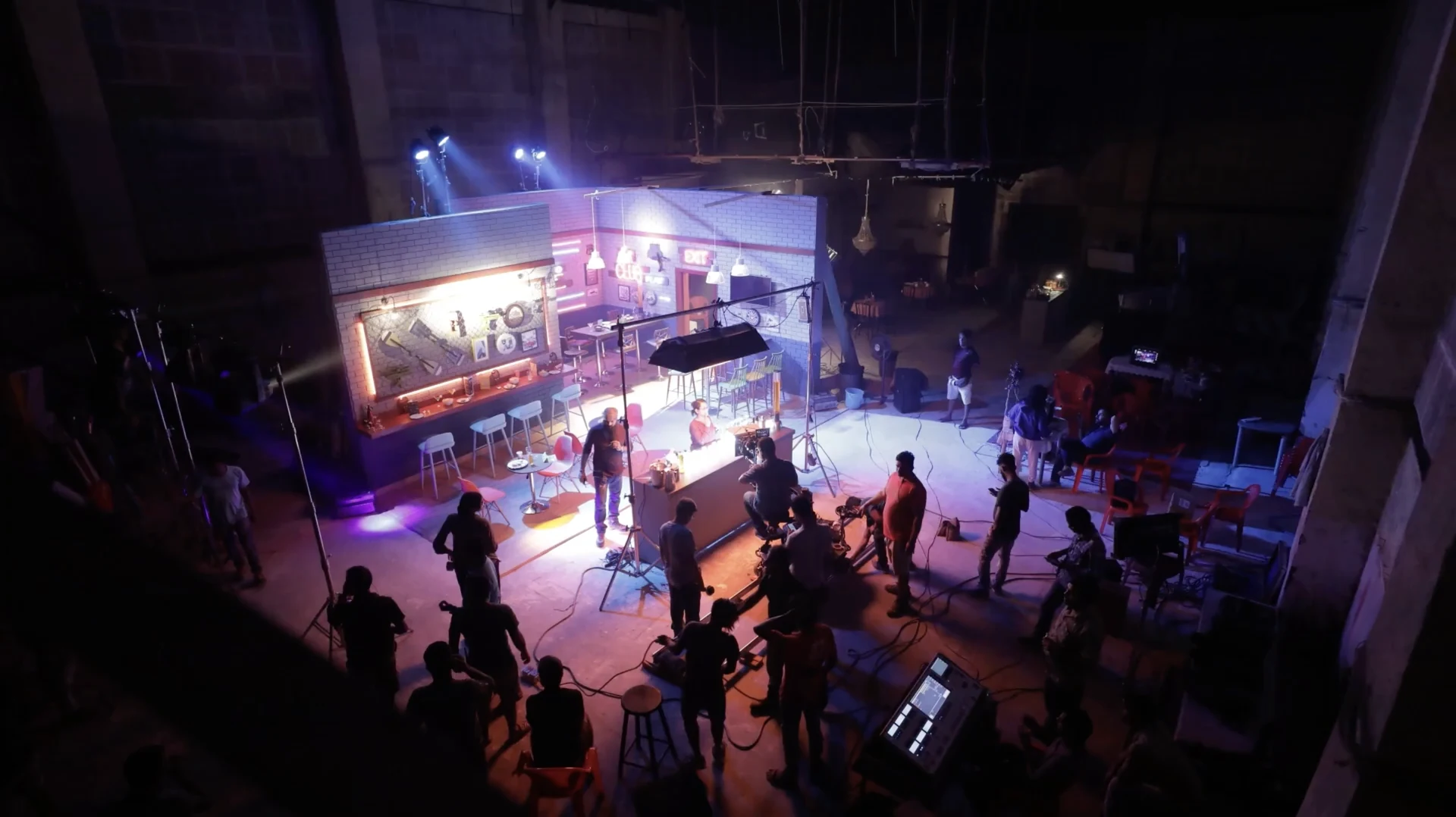 Film crew working on a brightly lit studio set.